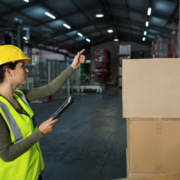 Jeune femme travaillant en entrepôt qui cherche à vérifier la plaque de charge avant de déposer ses cartons