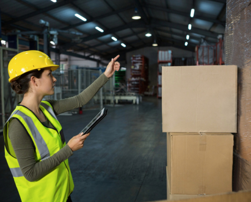 Jeune femme travaillant en entrepôt qui cherche à vérifier la plaque de charge avant de déposer ses cartons